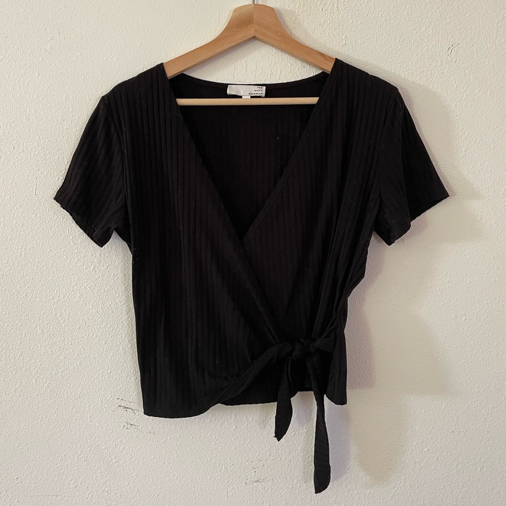 Ribbed black wrap-style top with tie. Fits snug on the body and is a cropped fit